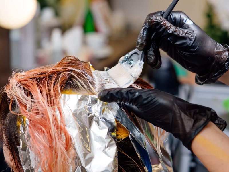 hairdresser coloring hair of her customer. Process of dyeing hair at beauty salon, coloring hair, top view, close up